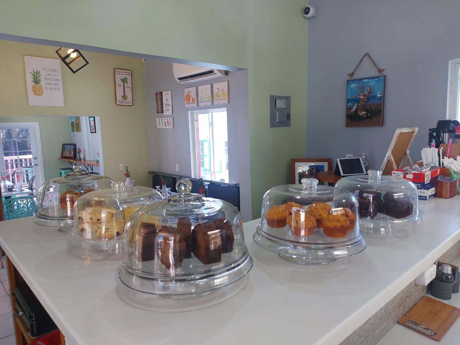Wide view of the café counter, its glass cake domes filled with banana bread, blondies, scones and muffins