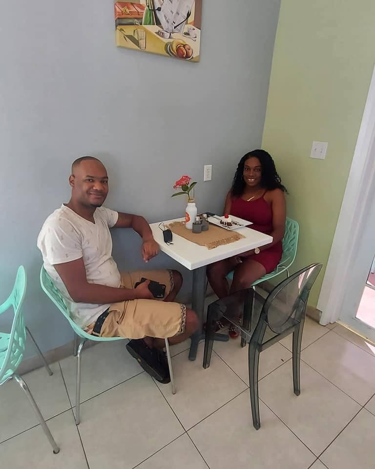 A couple sharing a table by the window, plates and a drink between them
