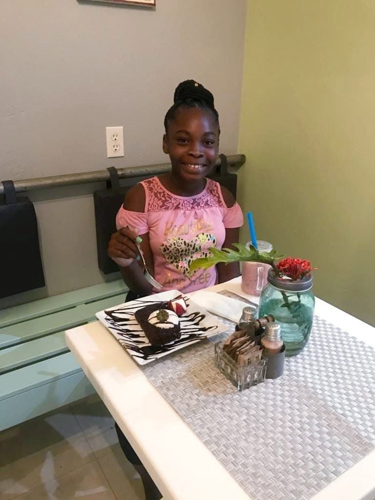A young guest smiling over her chocolate brownie dessert