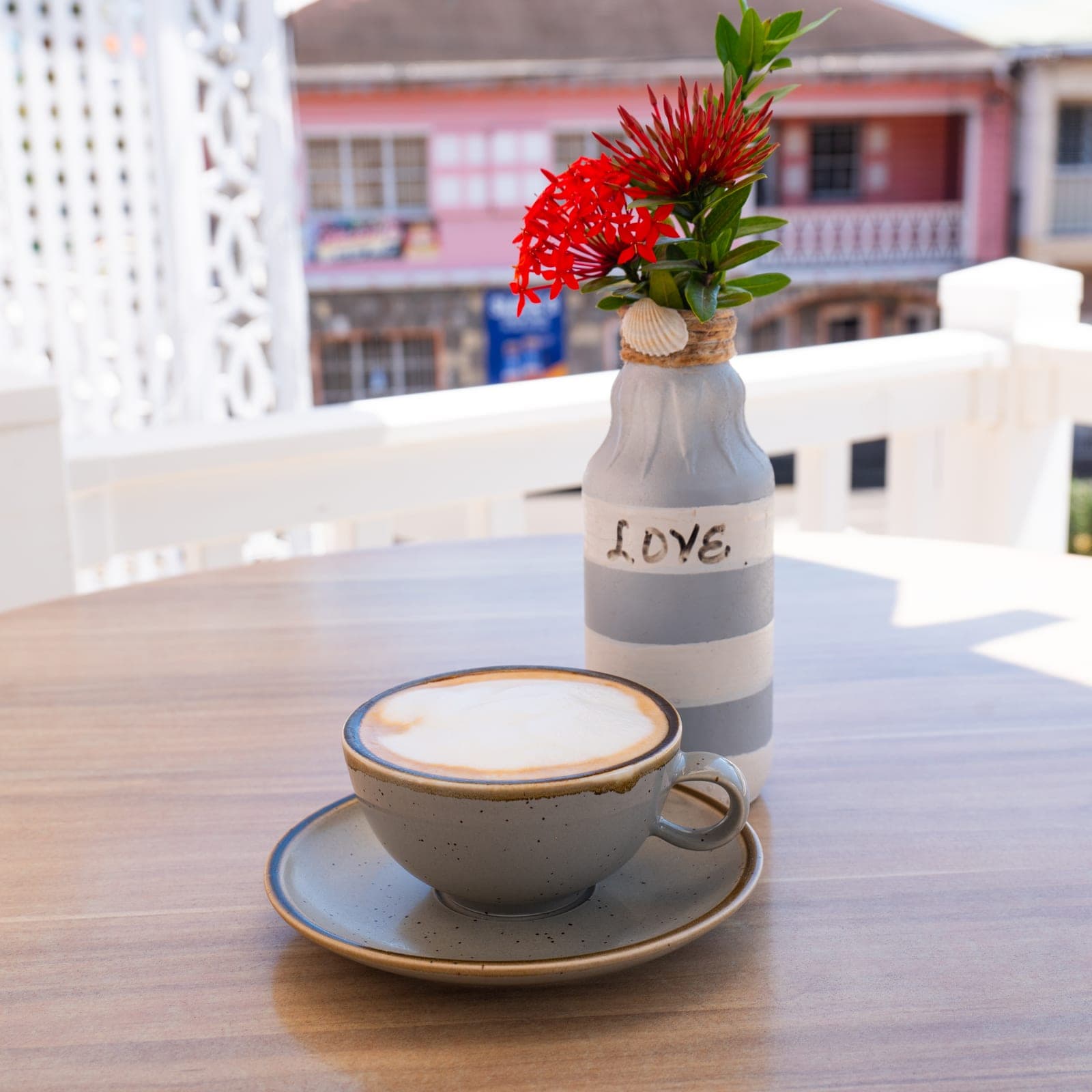 A cappuccino on a veranda table, Charlestown’s pink buildings behind